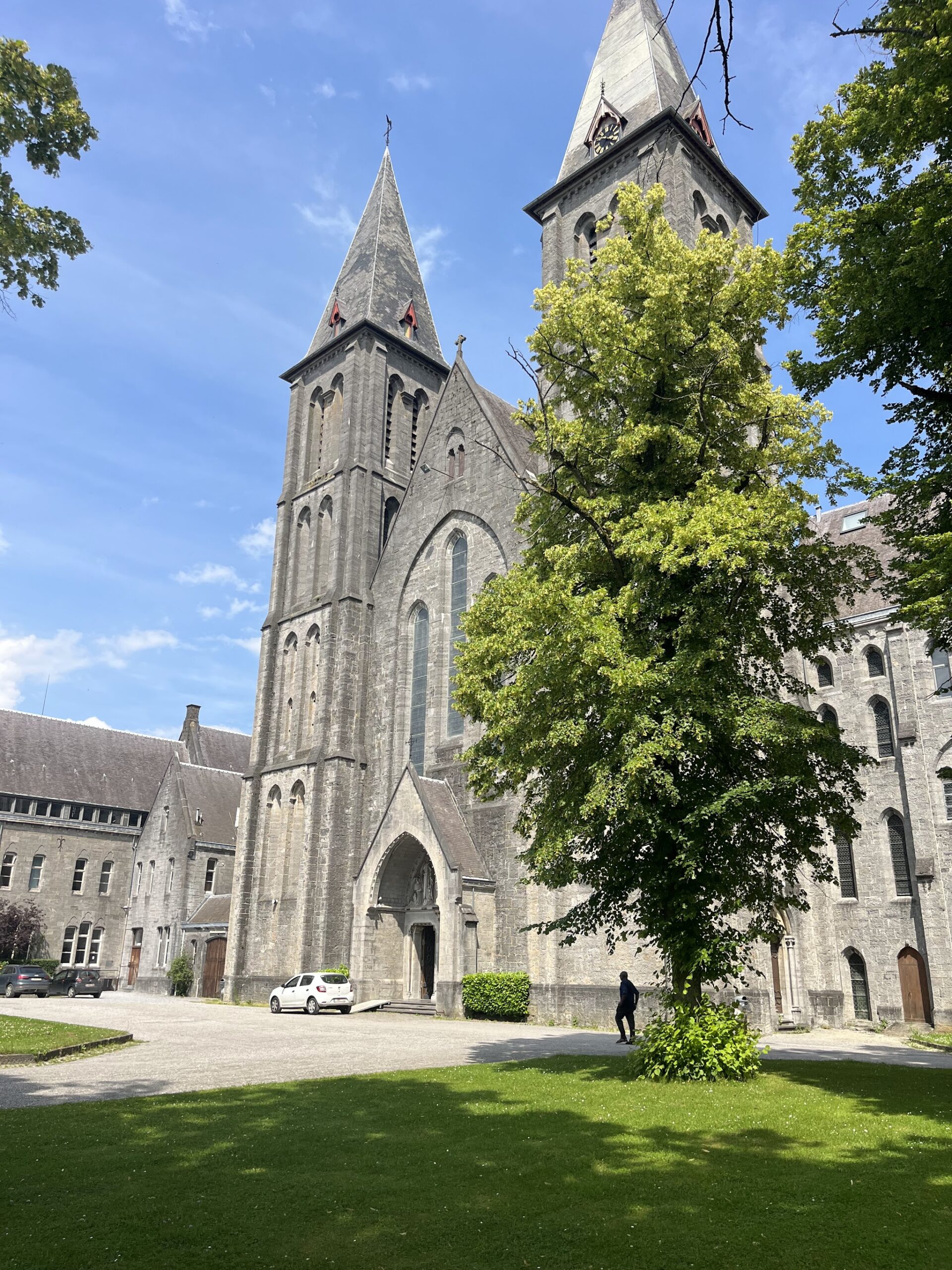 L’abbaye de Maredsous et ses clochers derrière les arbres du parc, par beau temps